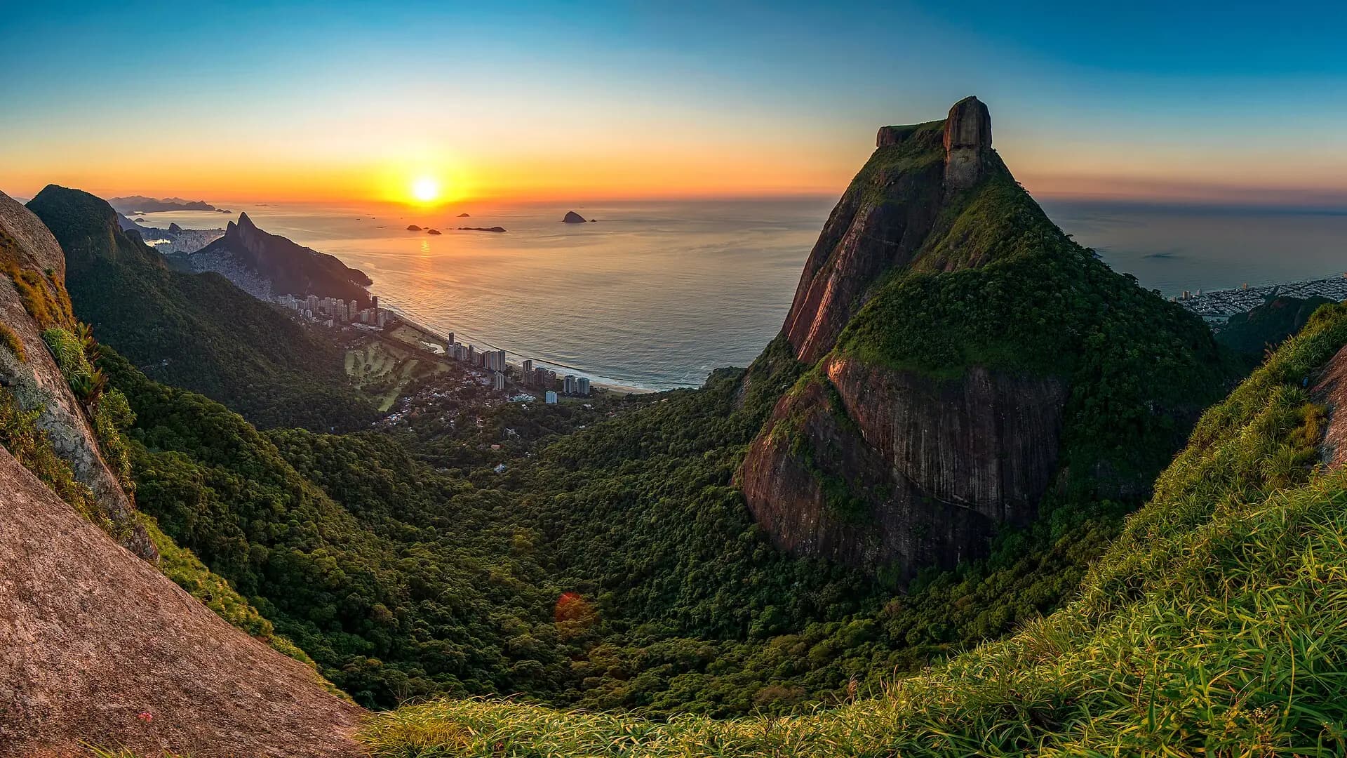 Nascer do sol sobre o mar visto da serra, com a Pedra da Gávea